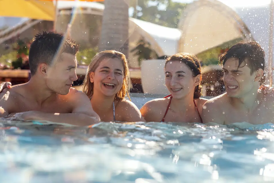 Friends laughing together in a sunny outdoor pool