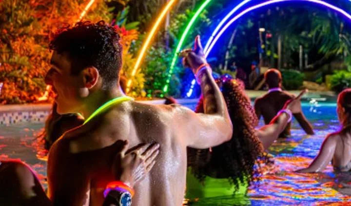 Guests enjoying colourful night lighting during AquaGlow at Aquatica San Antonio