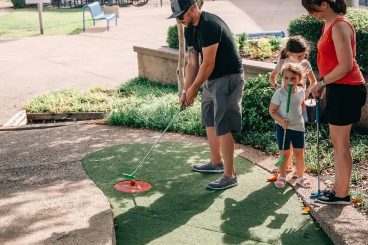 Family playing miniature golf in official Celebration Station brand photography