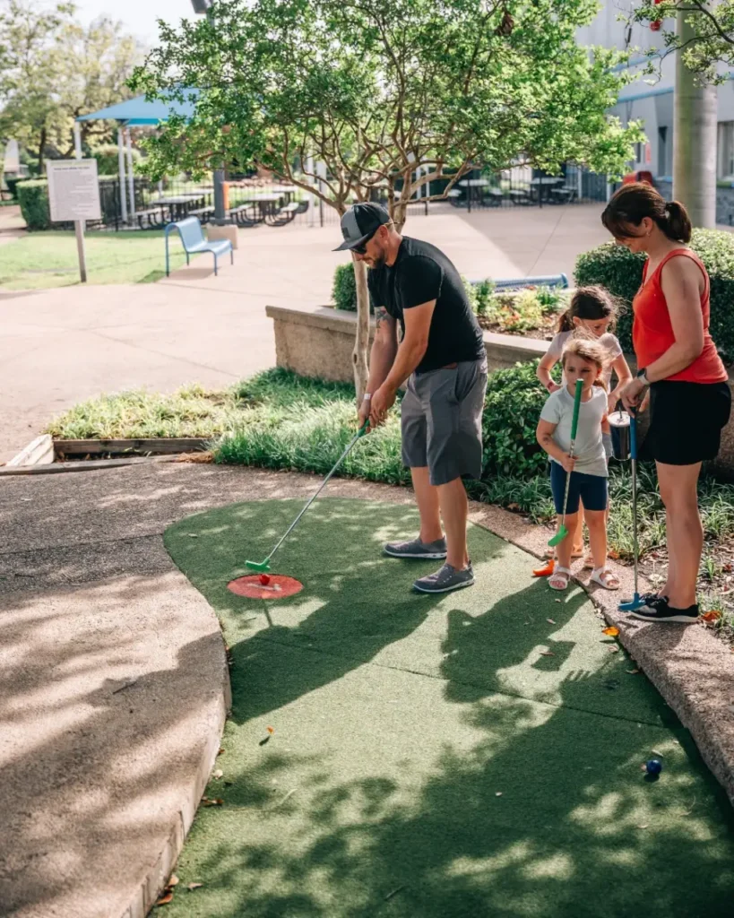 Family playing miniature golf in official Celebration Station brand photography