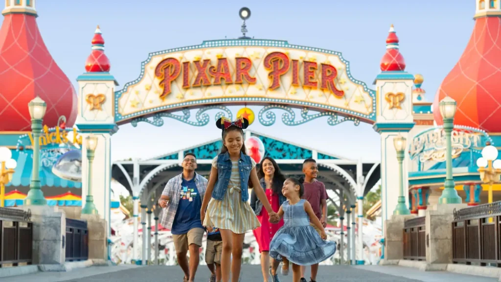 A family walks together past colorful attractions on Pixar Pier at Disney California Adventure.