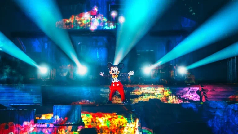 Mickey Mouse stands onstage amid beams of light during Fantasmic! at Disneyland Park.