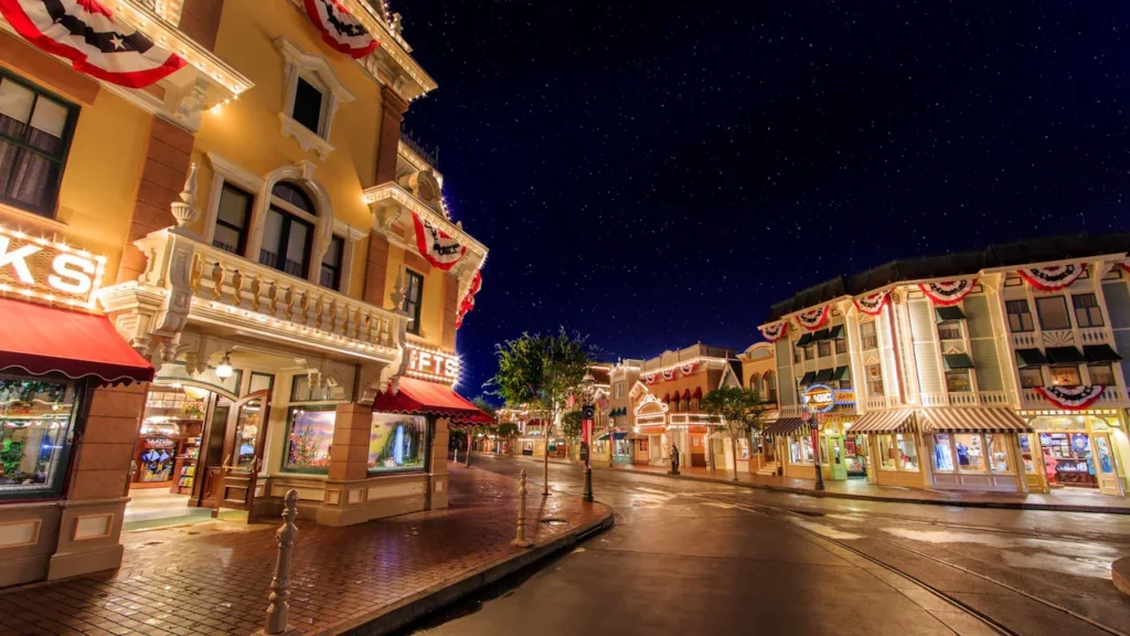 Illuminated storefronts line Main Street, U.S.A. at Disneyland Park after dark.