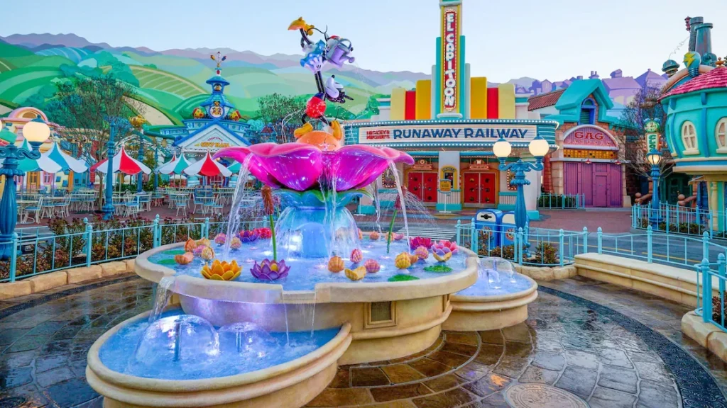 Mickey and Minnie’s fountain in Centoonial Park, with colorful Toontown buildings behind it at Disneyland Park.