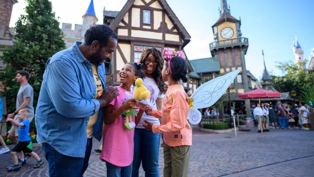 A family smiles together outside Peter Pan’s Flight, with Fantasyland’s clock tower behind them.