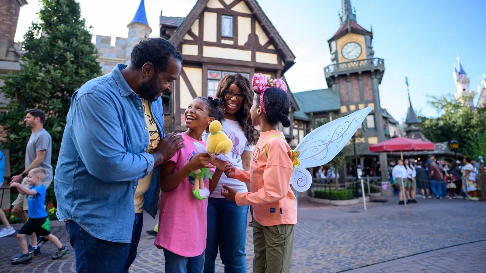 A family smiles together outside Peter Pan’s Flight, with Fantasyland’s clock tower behind them.
