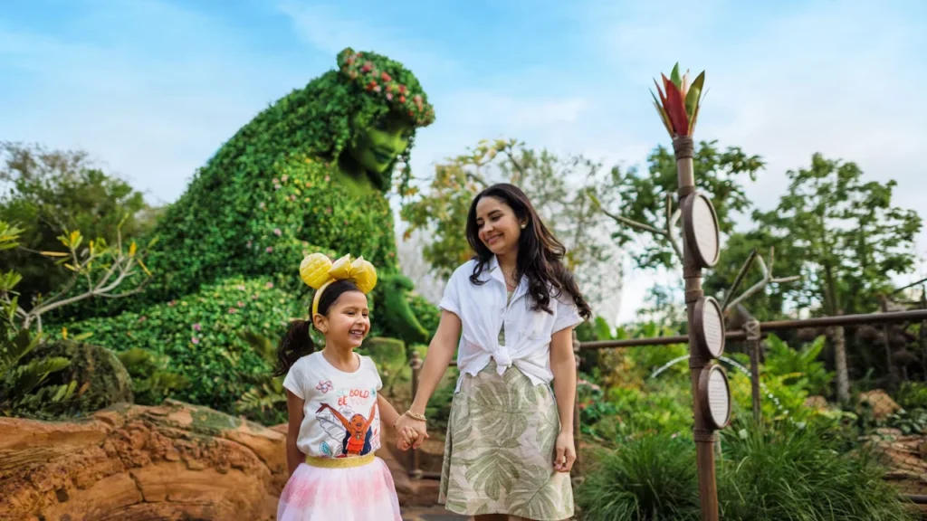 A mother and daughter stand beside the green Te Fiti figure at Journey of Water, Inspired by Moana, in EPCOT.