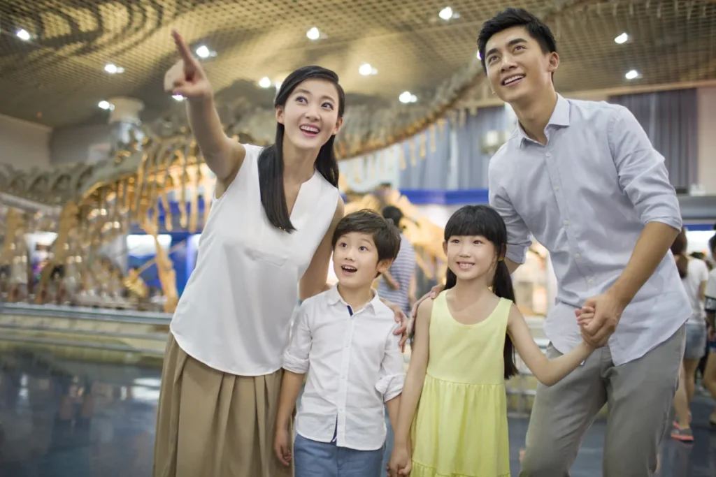 Two adults and two children stand together in a museum with a large dinosaur skeleton behind them.