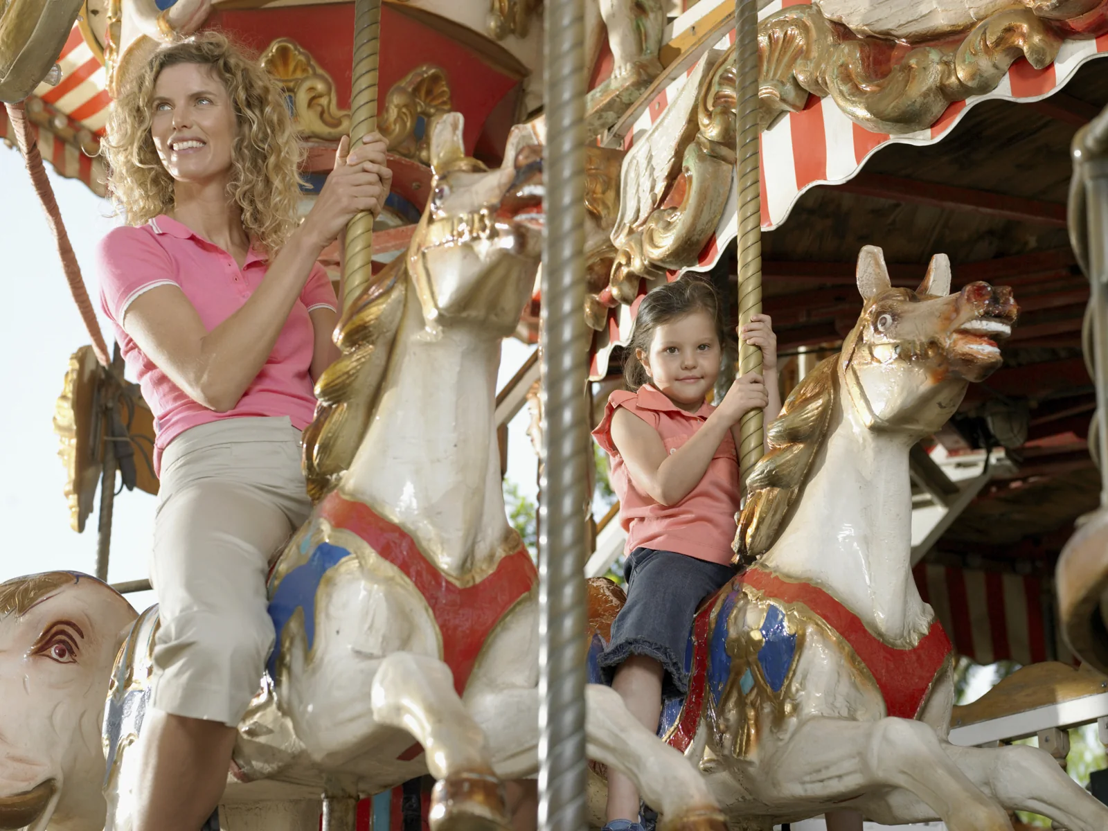 A woman and a child sit on ornate carousel horses.