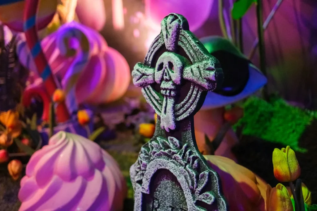 A decorative skull and crossbones tombstone stands among bright fantasy-style Halloween props.