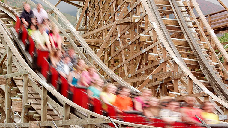 Riders in a red train travel along the wooden roller coaster track at Lagoon.