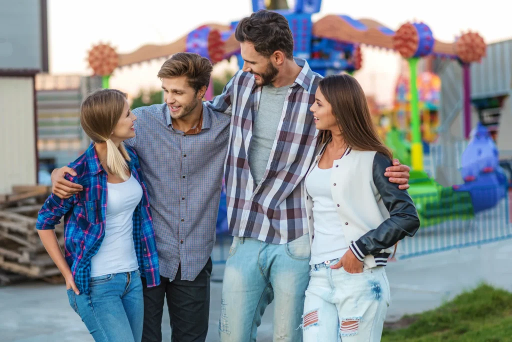 Four friends stand together near an outdoor amusement ride.