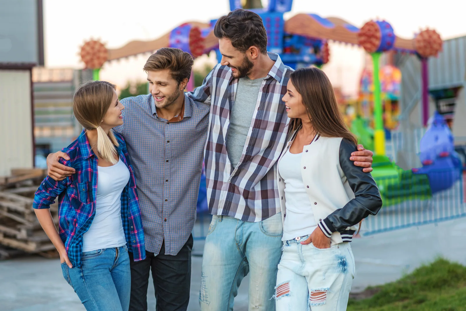 Four friends stand together near an outdoor amusement ride.
