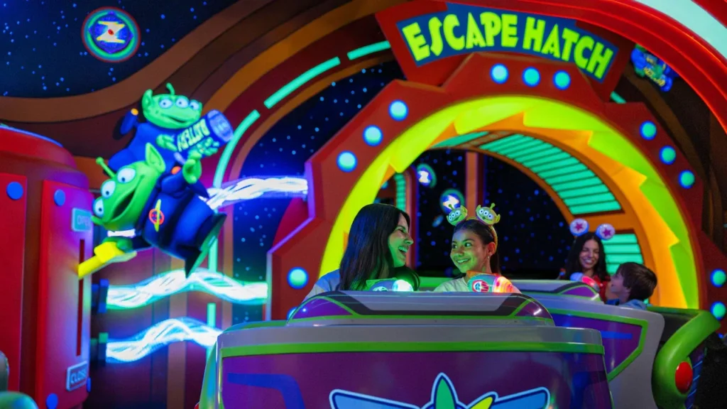A mother and daughter aim blasters from a ride vehicle on Buzz Lightyear’s Space Ranger Spin at Magic Kingdom.
