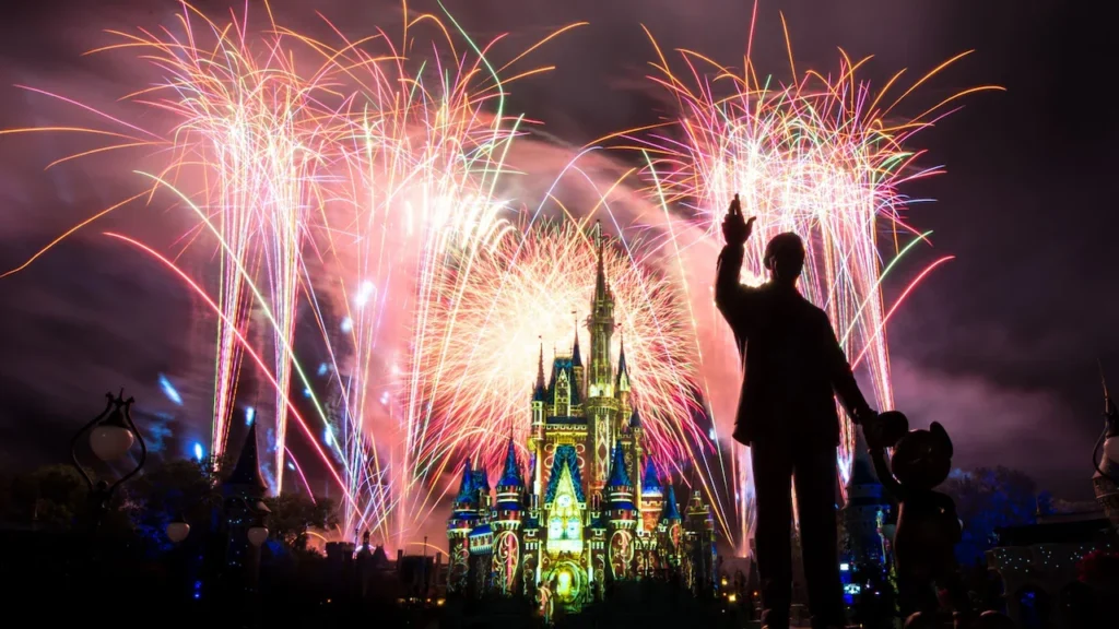 Fireworks burst above Cinderella Castle and the Partners statue at Magic Kingdom.