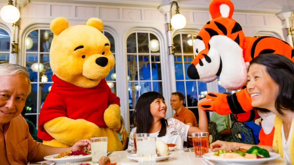 Winnie the Pooh and Tigger greet a family inside The Crystal Palace at Magic Kingdom.