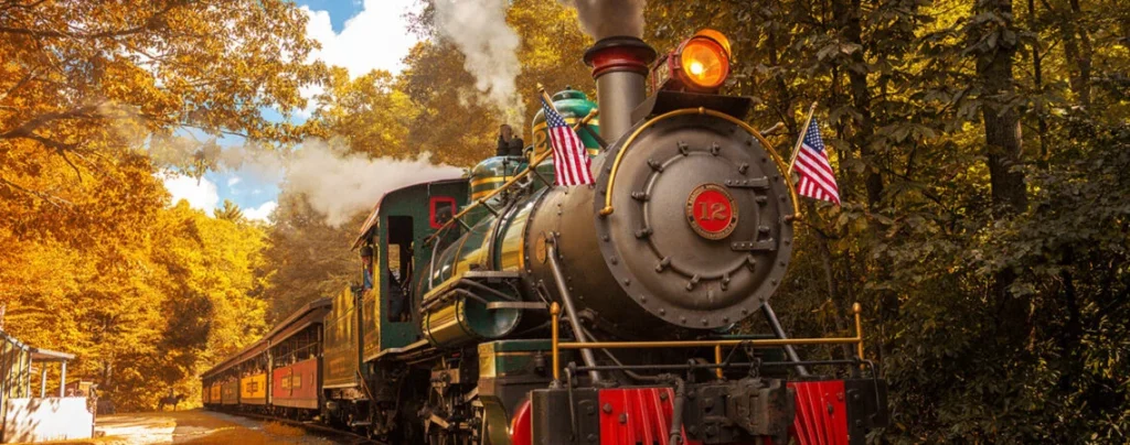 Steam locomotive No. 12 travelling through autumn trees at Tweetsie Railroad