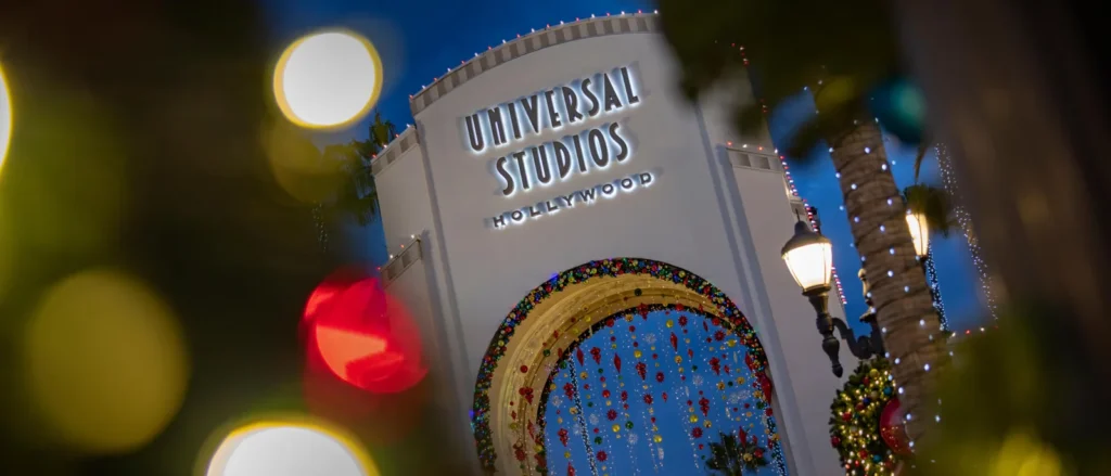 The Universal Studios Hollywood entrance arch glows with holiday lights after dark.
