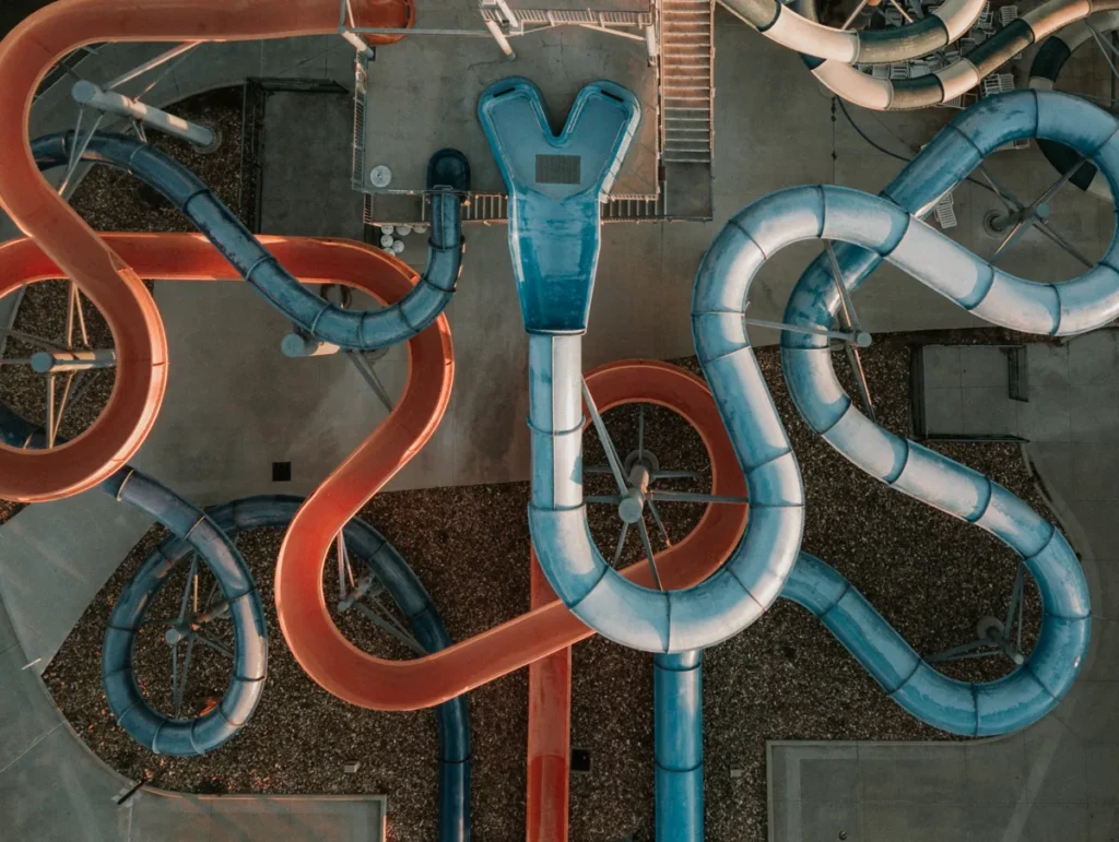 An aerial view shows orange and pale-blue water slides twisting above a water park deck.