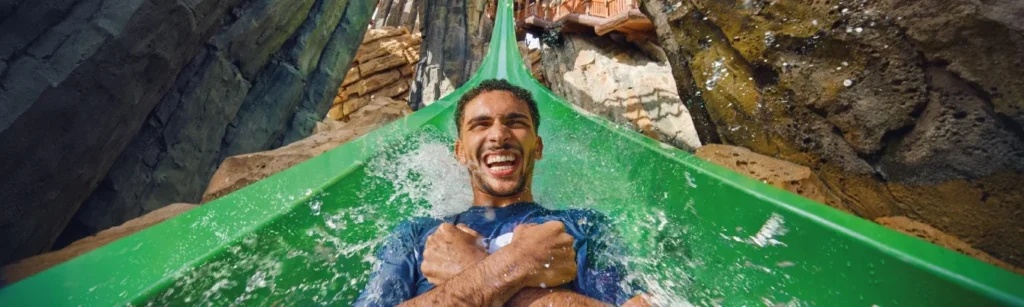 A guest descending the green Jebel Drop slide at Yas Waterworld Abu Dhabi