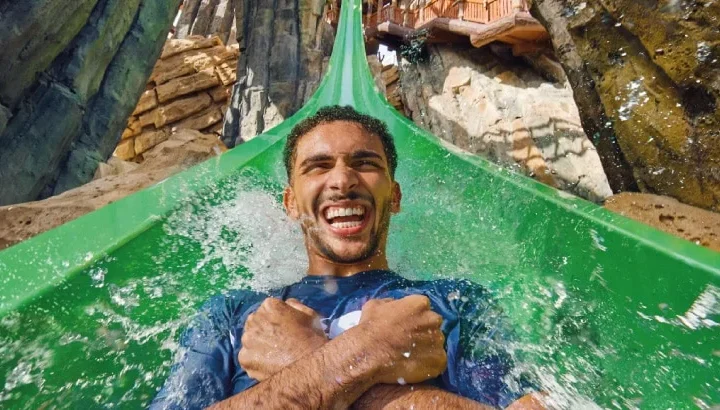 A guest descending the green Jebel Drop slide at Yas Waterworld Abu Dhabi