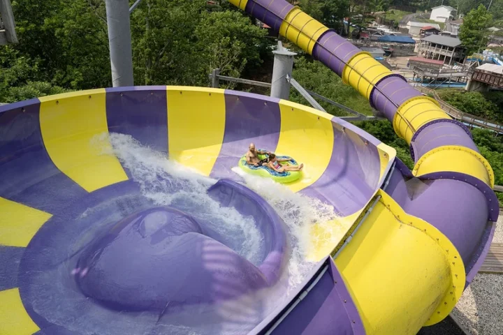 Raft riders circling the purple and yellow Typhoon Twister bowl at Zoom Flume
